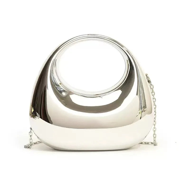 Le trompettiste porte un sac, un sac bandoulière en forme de croissant - un sac de soirée brillant, idéal pour les bals et les tenues à paillettes.